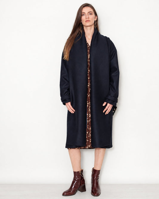 Manteau Aglaé marine en laine vierge porté ouvert en pied avec une robe et des bottines bordeaux.
