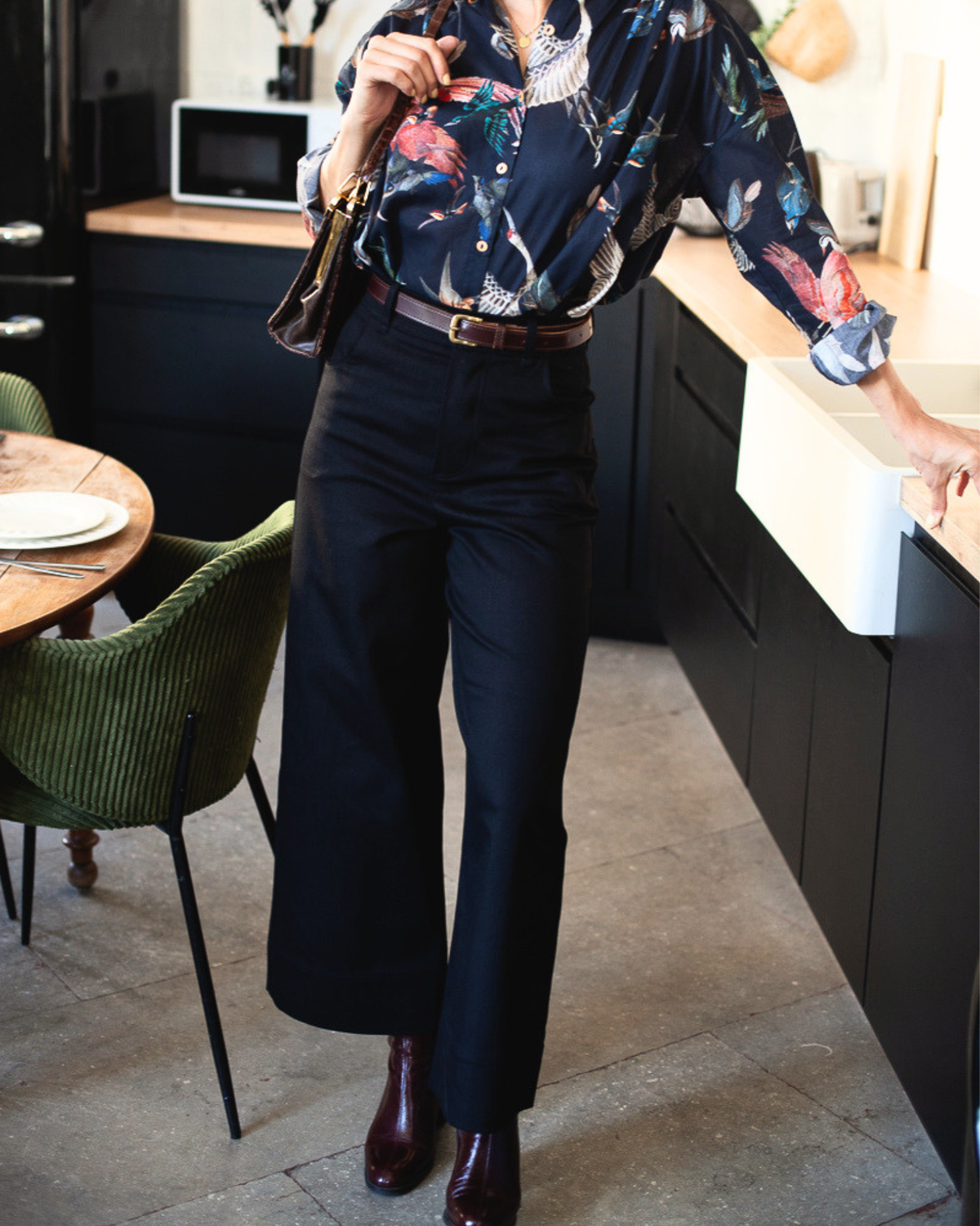 Pantalon Marinette denim bio noir porté de trois quarts avec une chemise imprimée, jambes larges.